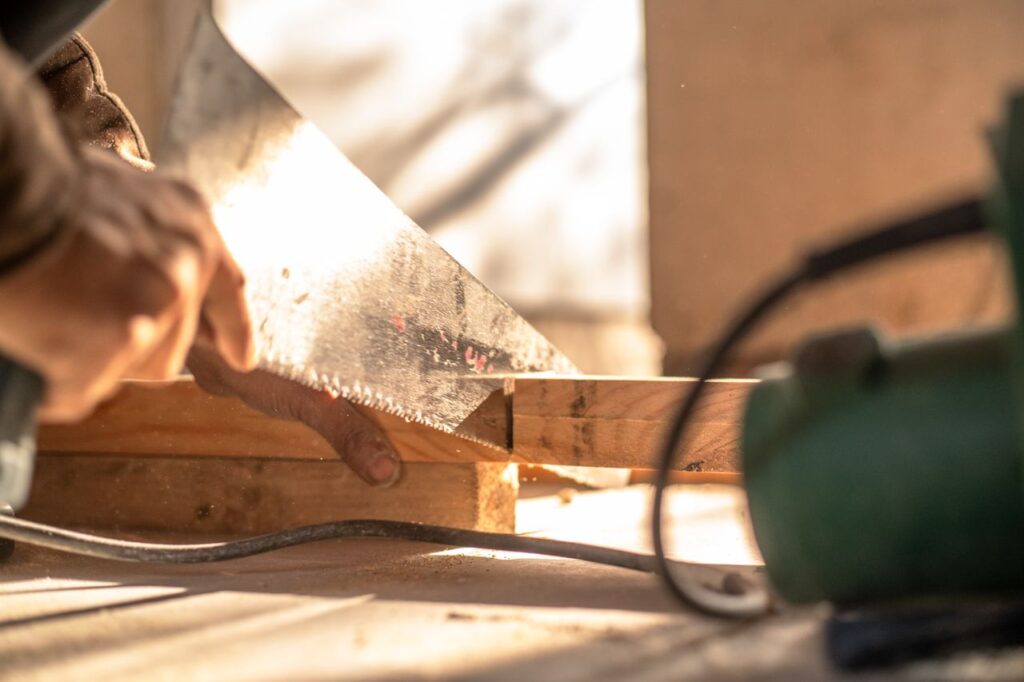 Carpenter cutting wood with a hand saw, showcasing craftsmanship and precision.